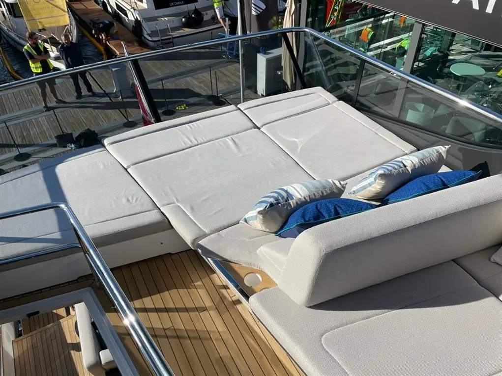 Luxurious yacht deck with cushioned seating and blue decorative pillows, showcasing a sunny marina view in the background.